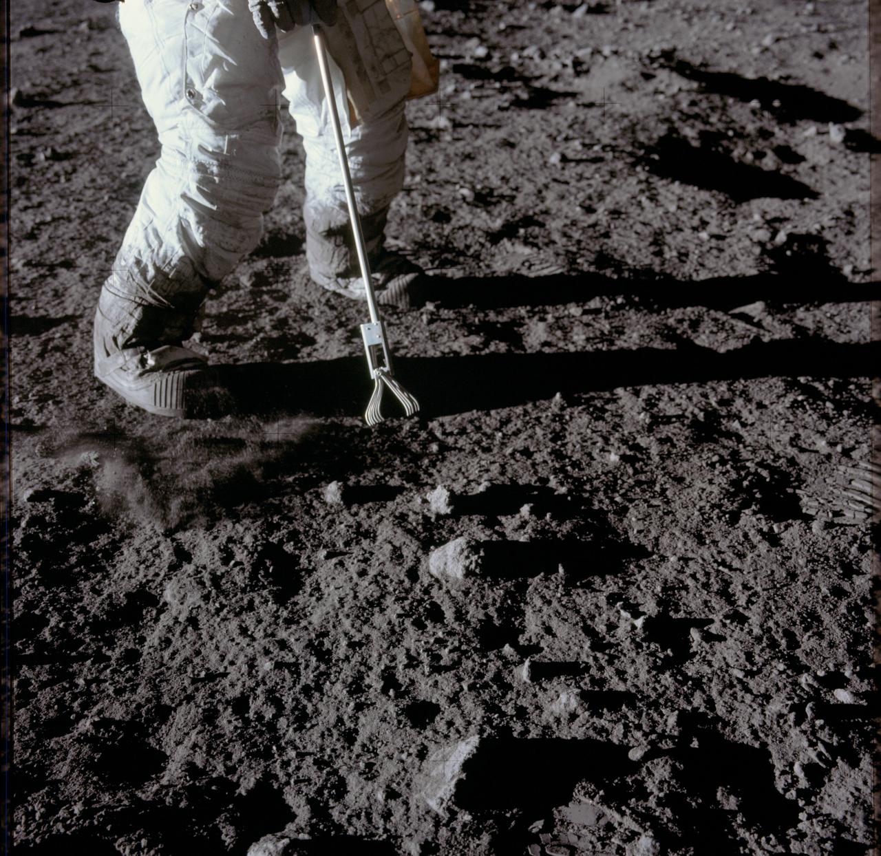 AS12-47-6932 (19 Nov. 1969) --- Close-up view of a set of tongs, an Apollo Lunar Hand Tool, being used by astronaut Charles Conrad Jr., commander, to pick up lunar samples during the Apollo 12 extravehicular activity. This photograph shows Conrad's legs and a good view of the lunar soil.