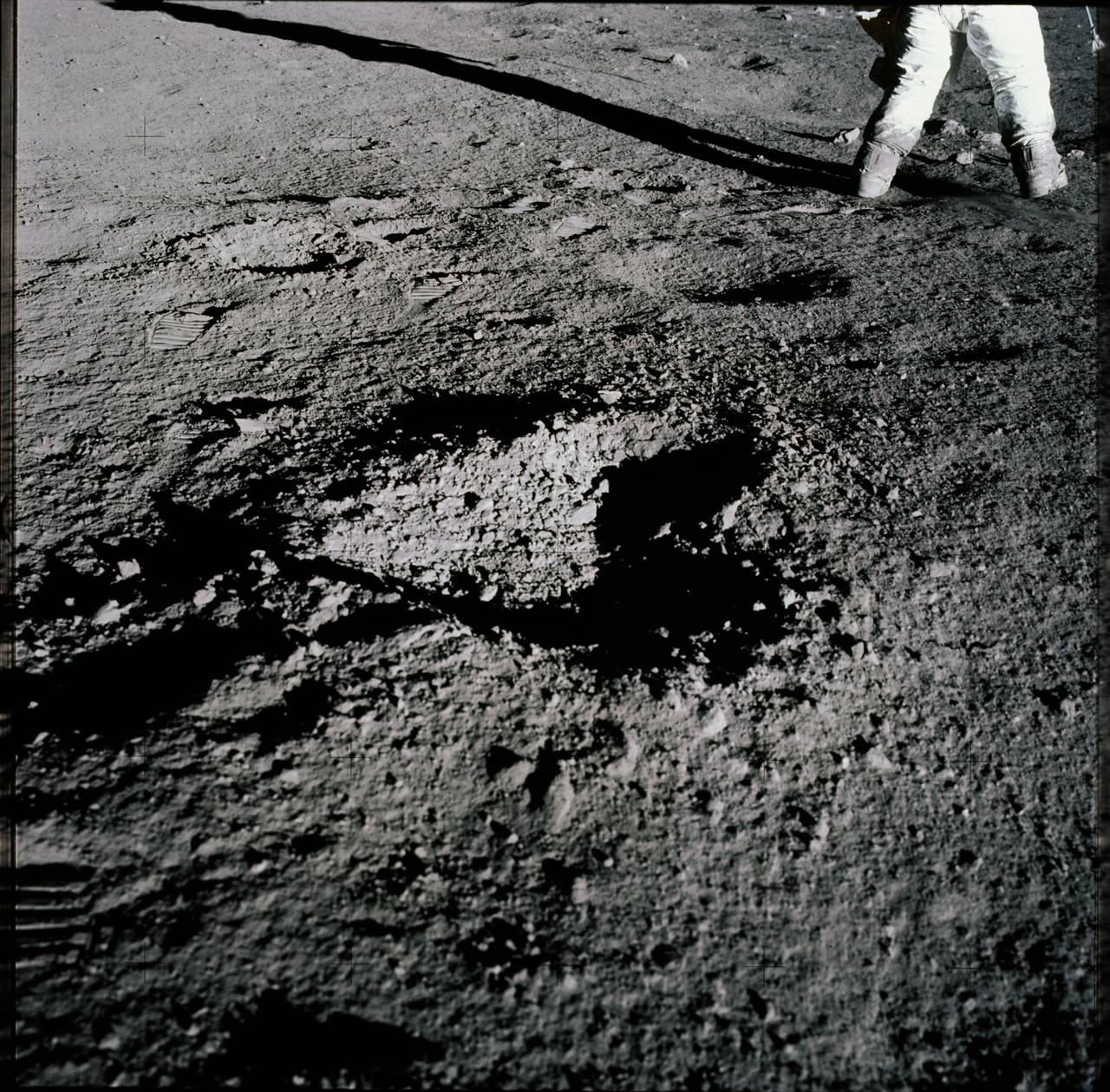 AS12-47-6938 (19 Nov. 1969) --- A close-up view of a heart-shaped depression (crater) in the lunar surface, as photographed during the Apollo 12 extravehicular activity (EVA). The legs of astronaut Charles Conrad Jr., commander, can be seen in the background. Astronaut Richard F. Gordon Jr., command module pilot, remained with the Command and Service Modules (CSM) in lunar orbit while astronauts Conrad and Alan L. Bean, lunar module pilot, descended in the Lunar Module (LM) to explore the moon.