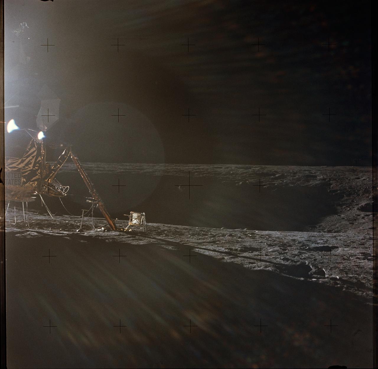 AS12-47-6949 (19-20 Nov. 1969) --- A photograph of the Apollo 12 lunar landing site taken during the extravehicular activity (EVA) of astronauts Charles Conrad Jr., commander; and Alan L. Bean, lunar module pilot. The Apollo 12 Lunar Module (LM) is on the left. Barely visible in the center of the picture, in the shadows on the farside of the crater, is the Surveyor 3 spacecraft. The two spacecraft are about 600 feet apart. Conrad and Bean walked over to Surveyor 3 during their second EVA. The television camera and several other pieces were taken from Surveyor 3 and brought back to Earth for scientific examination. Astronaut Richard F. Gordon Jr., command module pilot, remained with the Command and Service Modules (CSM) in lunar orbit, while astronauts Conrad and Bean descended in the LM to explore the moon. The considerable glare in the picture is caused by the position of the sun. The Apollo tool carrier is the object next to the LM footpad.