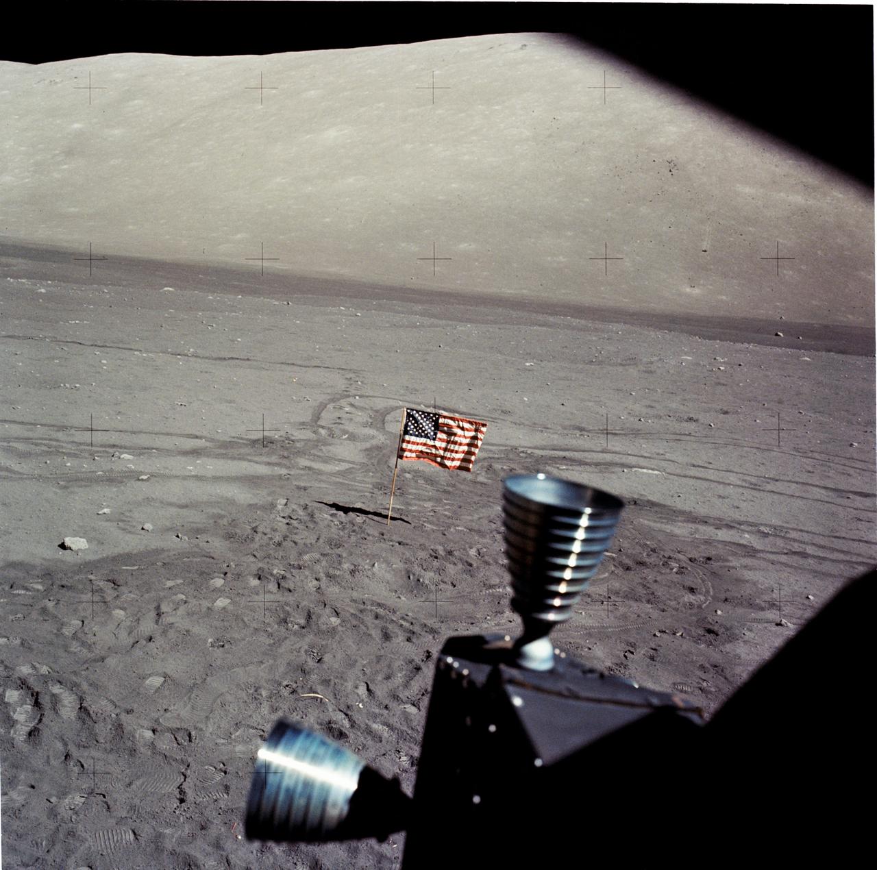 AS17-145-22216 (7-19 Dec. 1972) --- In this view looking out the Lunar Module (LM) windows shows the United States Flag on the moon's surface. This view looks toward the north Massif. The LM thrusters can be seen in foreground. While astronauts Eugene A. Cernan, commander, and Harrison H. Schmitt, lunar module pilot, descended in the LM "Challenger" to explore the Taurus-Littrow region of the moon, astronaut Ronald E. Evans, command module pilot, remained with the Command and Service Modules (CSM) "America" in lunar orbit.