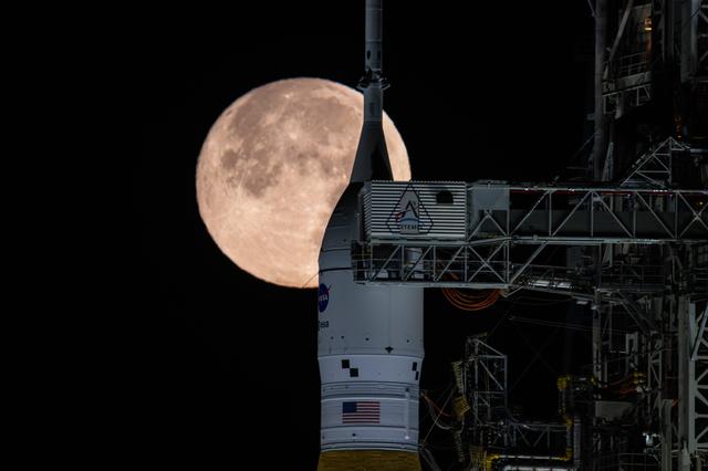 The Moon is seen shining over the SLS (Space Launch System) and Orion spacecr...