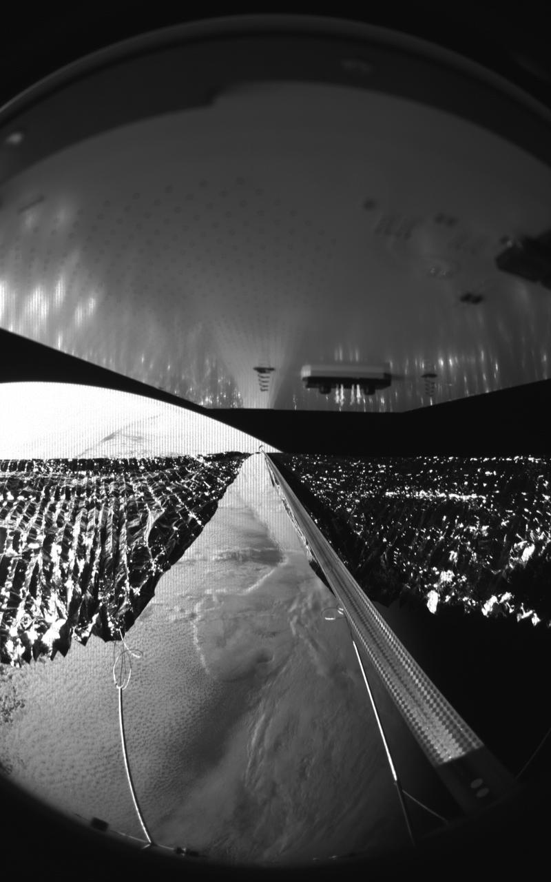 Four cameras aboard the Advanced Composite Solar Sail System spacecraft show the four reflective sail quadrants supported by composite booms. The booms are mounted at right angles and the spacecraft’s solar panel is rectangular, but lines appear distorted because of the wide-angle camera field of view.  View from a black-and-white wide-angle camera aboard the Advanced Composite Solar Sail System taken during sail unfurling in low Earth orbit. The spacecraft has four such cameras, centrally located aboard the spacecraft. Here, reflective sail quadrants supported by composite booms are seen when the booms are partially extended and the sail quadrants are not taut. At the top of the photo is the back surface of one of the spacecraft’s solar panels.  On the lower left Earth is seen below.