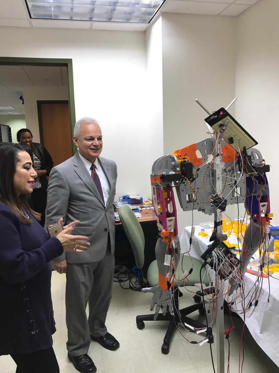 Norfolk State University Associate Professor Rasha Morsi showcases a phone operated, 3D-printed robot sign language interpreter to NASA Chief Technologist Douglas Terrier during a tour of the university’s Creative Gaming Simulation lab on February 6, 2018. (Credit: NASA)