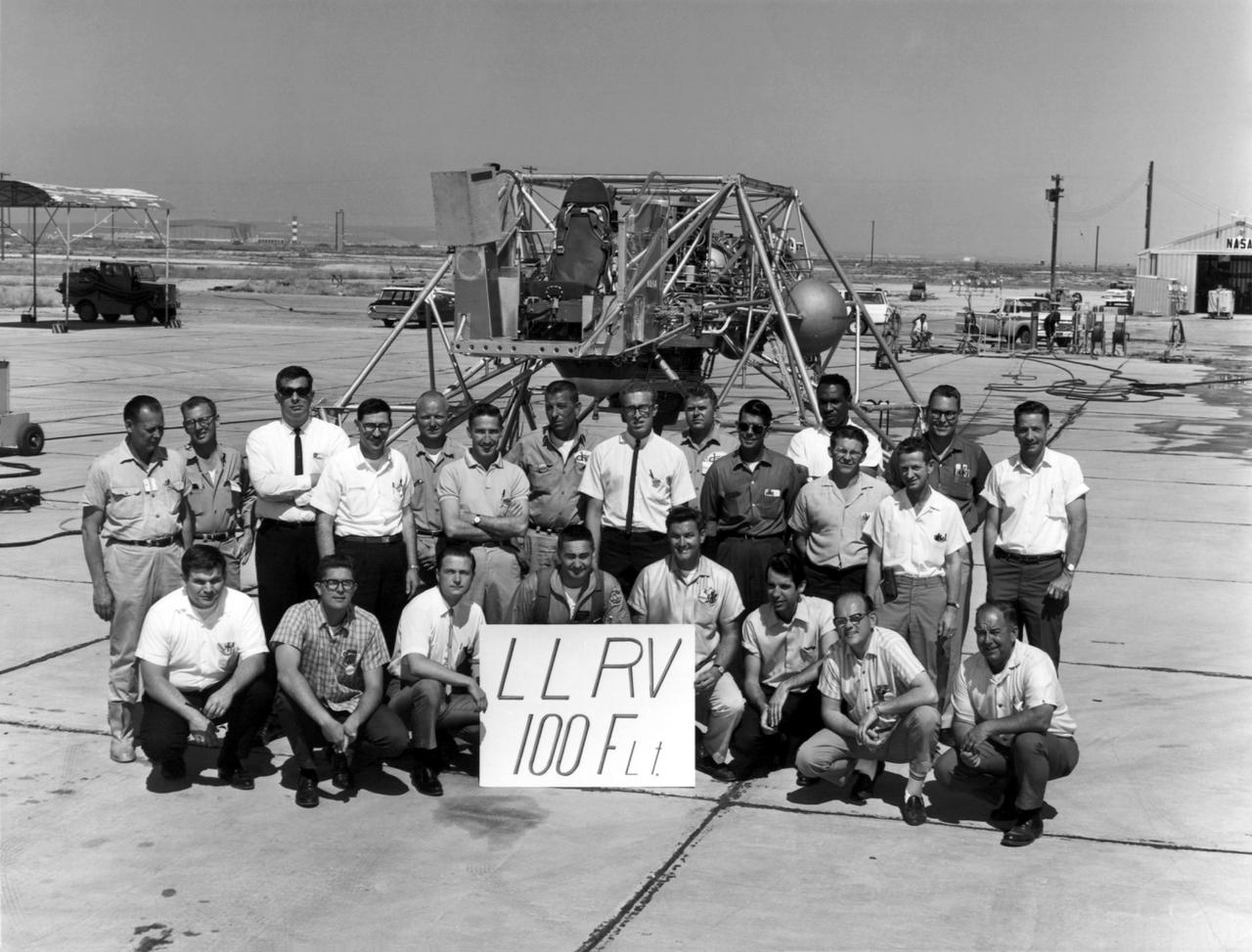A group photo of the LLRV personnel following the program's 100th flight. The photo was taken at South Base, and was near the hangar first used by the original NACA group, at what was then called Muroc. When Apollo planning was underway in 1960, NASA was looking for a simulator to profile the descent to the moon's surface. Three concepts surfaced: an electronic simulator, a tethered device, and the ambitious Dryden contribution, a free-flying vehicle. All three became serious projects, but eventually the NASA Flight Research Center's (FRC) Landing Research Vehicle (LLRV) became the most significant one. Hubert M. Drake is credited with originating the idea, while Donald Bellman and Gene Matranga were senior engineers on the project, with Bellman, the project manager. Simultaneously, and independently, Bell Aerosystems Company, Buffalo, N.Y., a company with experience in vertical takeoff and landing (VTOL) aircraft, had conceived a similar free-flying simulator and proposed their concept to NASA headquarters. NASA Headquarters put FRC and Bell together to collaborate. The challenge was; to allow a pilot to make a vertical landing on Earth in a simulated moon environment, one sixth of the Earth's gravity and with totally transparent aerodynamic forces in a "free flight" vehicle with no tether forces acting on it.  Built of tubular aluminum like a giant four-legged bedstead, the vehicle was to simulate a lunar landing profile from around 1500 feet to the moon's surface. To do this, the LLRV had a General Electric CF-700-2V turbofan engine mounted vertically in gimbals, with 4200 pounds of thrust. The engine, using JP-4 fuel, got the vehicle up to the test altitude and was then throttled back to support five-sixths of the vehicle's weight, simulating the reduced gravity of the moon. Two hydrogen-peroxide lift rockets with thrust that could be varied from 100 to 500 pounds handled the LLRV's rate of descent and horizontal translations. Sixteen smaller hydrogen-peroxide r