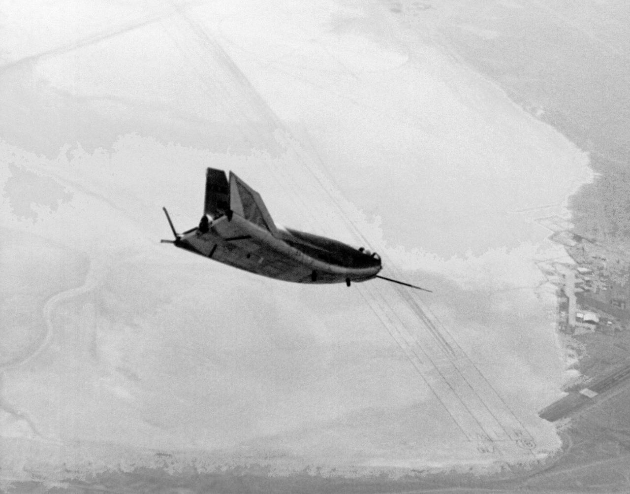 The HL-10 Lifting Body is seen here in flight over Rogers Dry lakebed. Like the other lifting bodies, the HL-10 made a steep descent toward the lakebed, followed by a high-speed landing. This was due to the vehicle's low lift-over-drag ratio. The first 11 flights of the HL-10 were unpowered, flown to check the vehicle's handling and stability before rocket-powered flights began using the XLR-11 rocket engine.