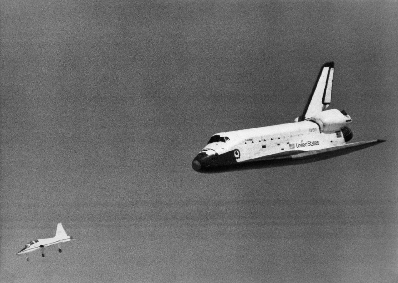 The Space Shuttle Columbia glides down over Rogers Dry Lake as it heads for a landing at Edwards Air Force Base at the conclusion of its first orbital mission on April 14, 1981.