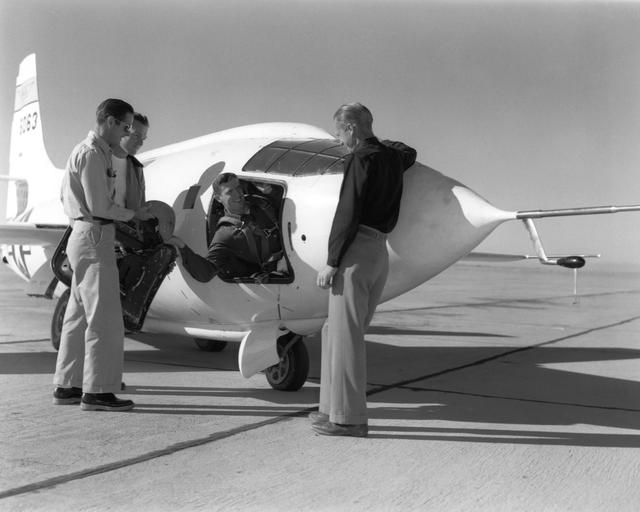 NASA image: NACA pilot John Griffith hands his flight gear to Dick Payne as crew members Ed Edwards and Clyde Bailey look on.