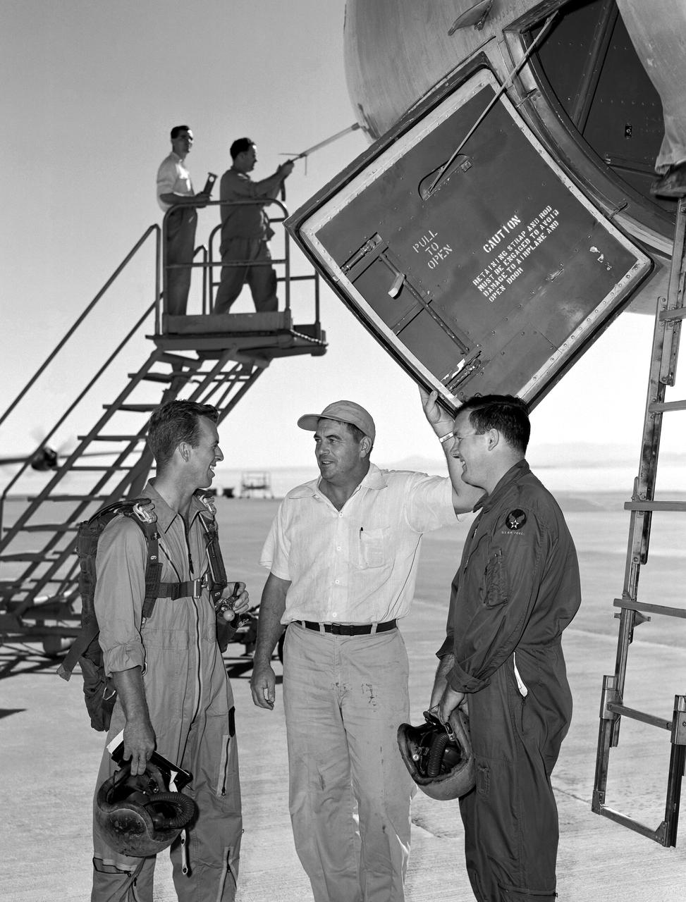 B-47A Stratojet on ramp with pilots and crew.  In 1954 after a research flight in the Boeing B-47A Stratojet Crew Chief Wilbur McClenaghan (center) asks of the pilots if there are any "squawks" that should be taken care of before the next flight. Pilots are Joe Walker on the viewer's left and Stanley Butchart on the right. Data system technician Merle Curtis, in coveralls, is busy checking the airdata head mounted on the nose boom with the help of Instrumentation Crew Chief Raymond Langley.   The door to the cockpit area is open showing a view of the ladder that folds down to be used by the pilots to enter and leave the area.