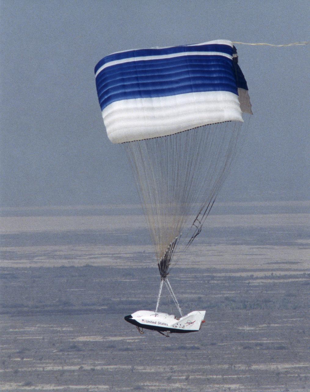 The X-38 technology demonstrator descends under its steerable parafoil toward a lakebed landing in a March 2000 test flight.