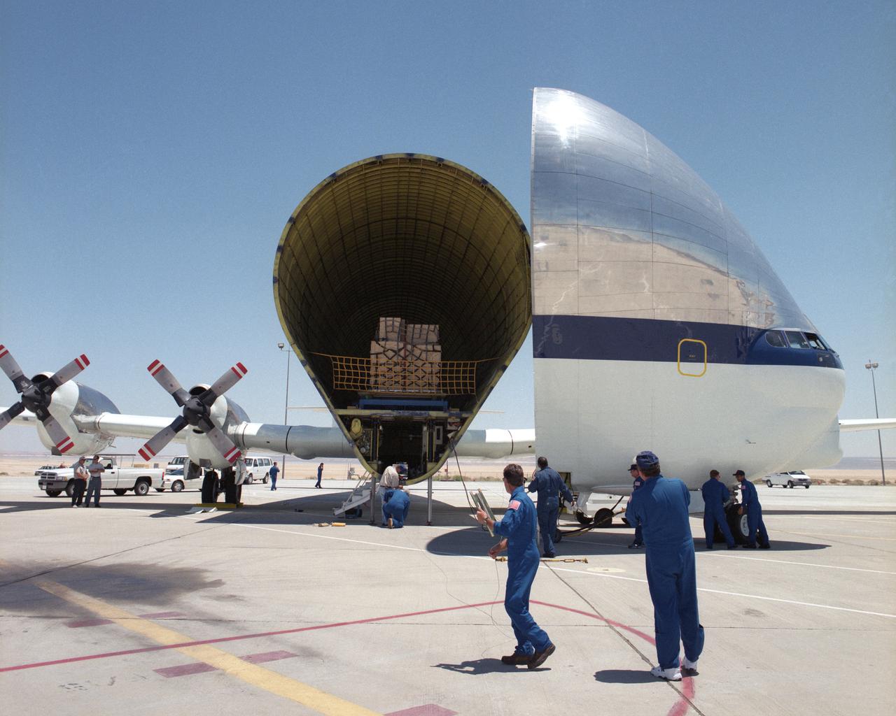 Members of the flight and ground crews prepare to unload equipment from NASA's B377SGT Super Guppy Turbine cargo aircraft on the ramp at NASA's Dryden Flight Research Center at Edwards Air Force Base, Calif. The outsize cargo plane had delivered the latest version of the X-38 flight test vehicle to NASA Dryden when this photo was taken on June 11, 2000.