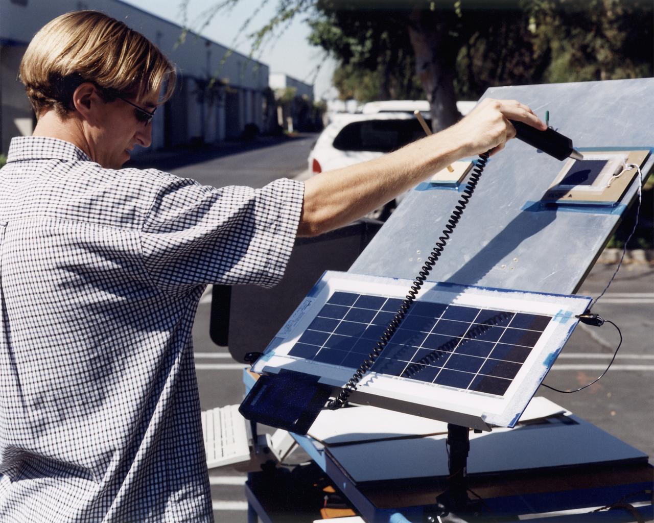 A technician at AeroVironment's Design Development Center in Simi Valley, California, checks a panel of silicon solar cells for conductivity and voltage. The bi-facial cells, fabricated by SunPower, Inc., of Sunnyvale, California, are among 64,000 solar cells which have been installed on the Helios Prototype solar-powered aircraft to provide power to its 14 electric motors and operating systems.