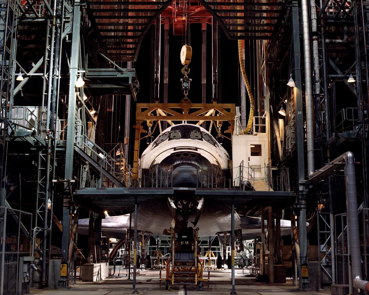 The Space Shuttle Discovery is centered in the Mate-Demate Device (MDD) at NASA’s Dryden Flight Research Center at Edwards, California. The gantry-like MDD structure is used for servicing the shuttle orbiters in preparation for their ferry flight back to the Kennedy Space Center in Florida, including mounting the shuttle atop NASA’s modified Boeing 747 Shuttle Carrier Aircraft.