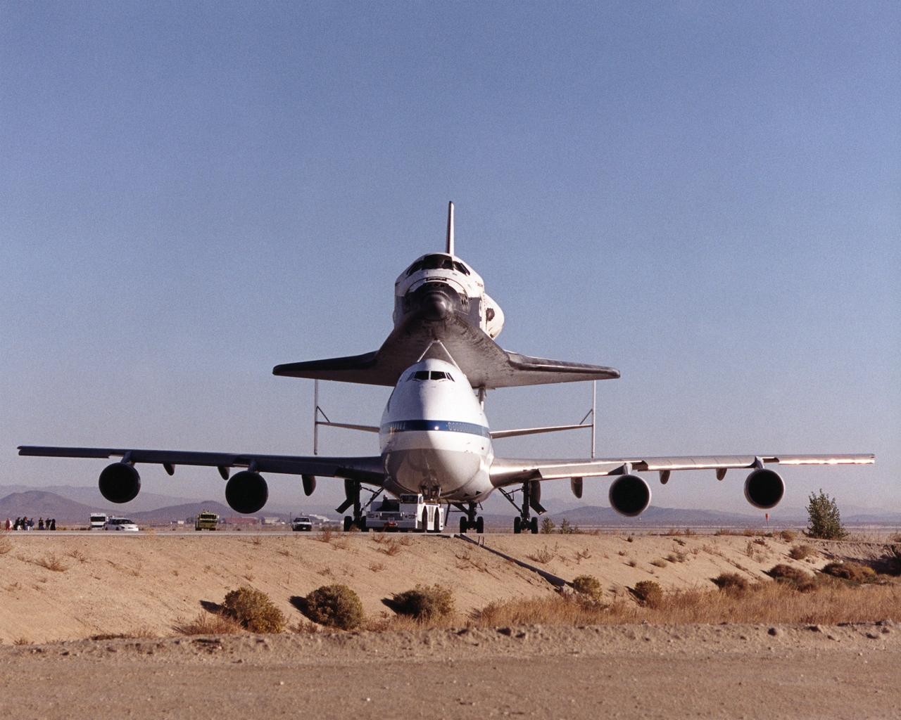 The Space Shuttle Discovery sits atop one of NASA’s modified Boeing 747 Shuttle Carrier Aircraft as the unusual piggyback duo is towed along a taxiway at NASA’s Dryden Flight Research Center at Edwards, California. The Discovery was ferried from NASA Dryden to NASA’s Kennedy Space Center in Florida on November 2, 2000, after extensive pre-ferry servicing and preparations.