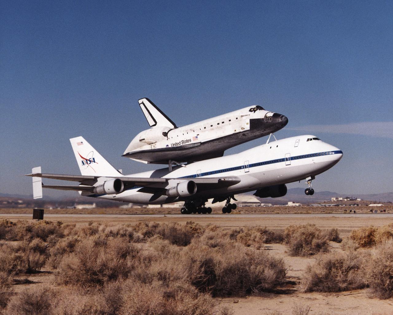 Carrying the Space Shuttle Discovery piggyback, one of NASA’s modified Boeing 747 Shuttle Carrier Aircraft lifts off the runway at Edwards Air Force Base, California. The Discovery was ferried from NASA’s Dryden Flight Research Center at Edwards to NASA’s Kennedy Space Center in Florida on November 2, 2000, after extensive post-landing servicing and ferry flight preparations.