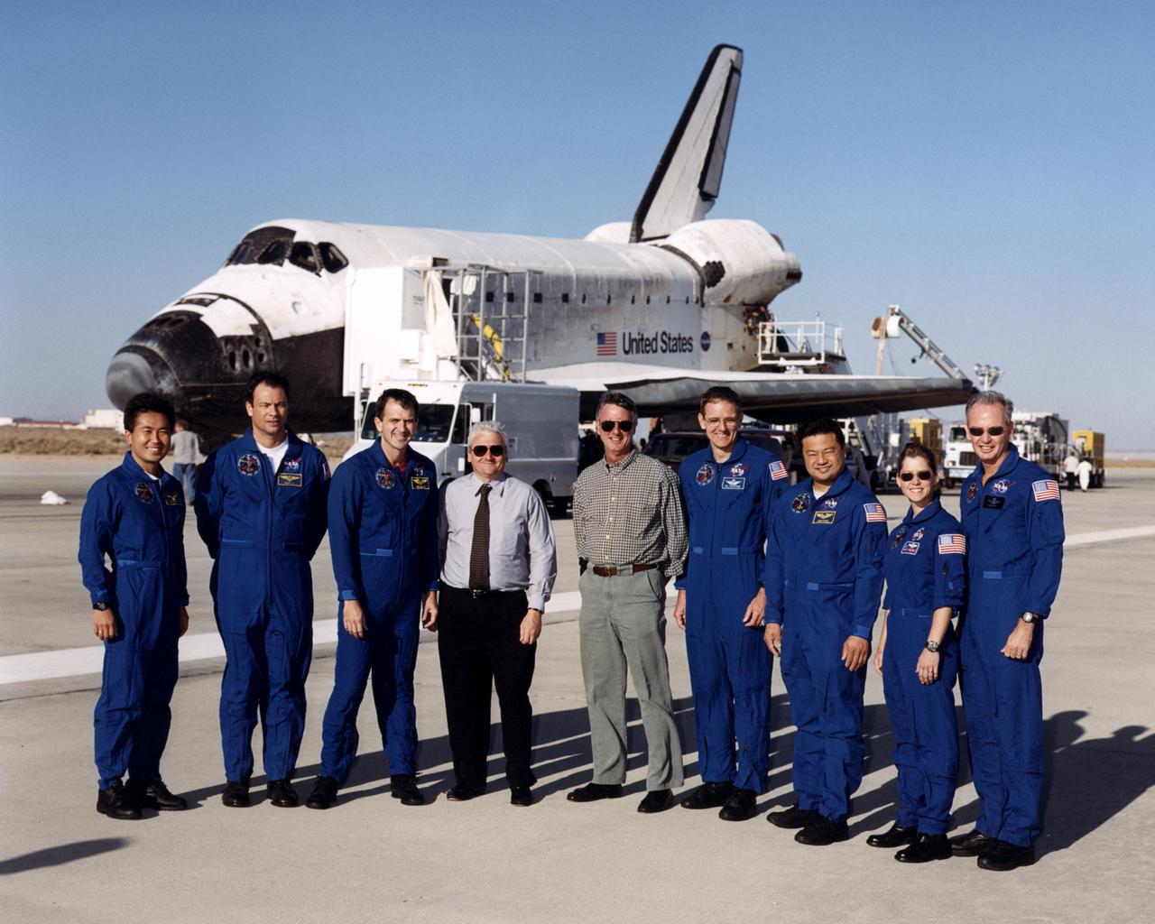 The seven-member crew of the Space Shuttle mission STS-92 gathered in front of the Shuttle Discovery shortly after landing at Edwards Air Force Base in Southern California October 24, 2000. They are seen here with NASA Dryden Fight Research Center Director Kevin Petersen and Deputy Director Wallace Sawyer. From left are mission specialists Koichi Wakata, Michael Lopez-Alegria, Jeff Wisoff, Bill McArthur and Leroy Chiao, pilot Pam Melroy and mission commander Brian Duffy. Between Jeff Wisoff and Brian McArthur are Kevin Petersen and Wally Sawyer, wearing ordinary civilian clothing.
