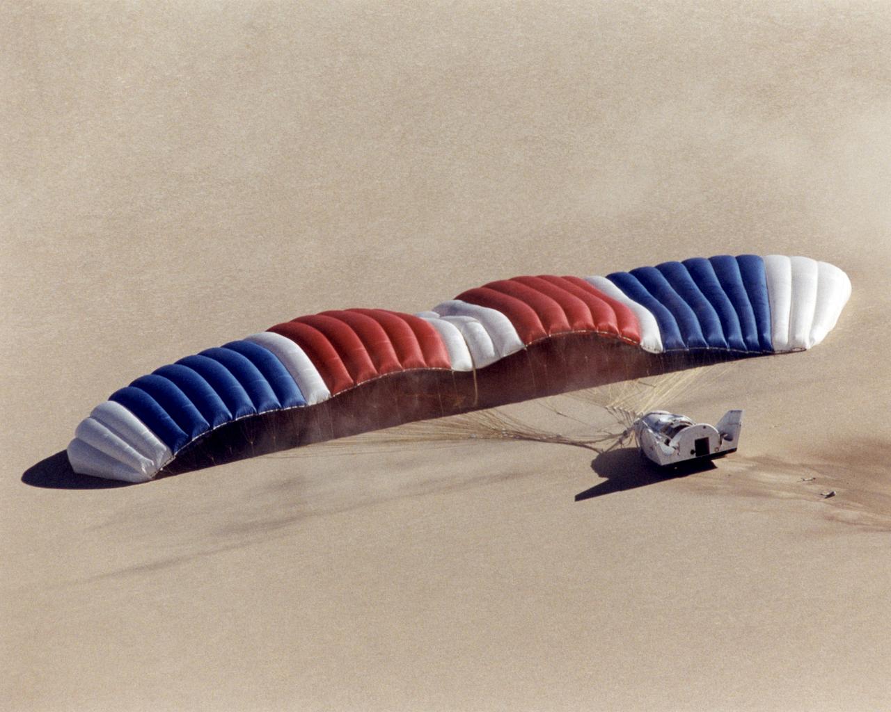 Looking like a giant air mattress, the world's largest parafoil slowly deflates seconds after it carried the latest version of the X-38, V-131R, to a landing on Rogers Dry Lake adjacent to NASAÕs Dryden Flight Research Center at Edwards, California, at the end of its first free flight, November 2, 2000. The X-38 prototypes are intended to perfect technology for a planned Crew Return Vehicle (CRV) "lifeboat" to carry a crew to safety in the event of an emergency on the International Space Station. Free-flight tests of X-38 V-131R are evaluating upgraded avionics and control systems and the aerodynamics of the modified upper body, which is more representative of the final design of the CRV than the two earlier X-38 test craft, including a simulated hatch atop the body. The huge 7,500 square-foot parafoil will enable the CRV to land in the length of a football field after returning from space. The first three X-38's are air-launched from NASA's venerable NB-52B mother ship, while the last version, V-201, will be carried into space by a Space Shuttle and make a fully autonomous re-entry and landing.