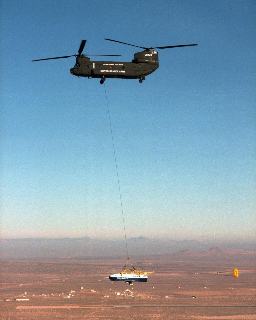 With a small stabilization parachute trailing behind, the X-40 sub-scale technology demonstrator is suspended under a U.S. Army CH-47 Chinook cargo helicopter during a captive-carry test flight at NASA's Dryden Flight Research Center, Edwards, California. The captive carry flights are designed to verify the X-40's navigation and control systems, rigging angles for its sling, and stability and control of the helicopter while carrying the X-40 on a tether. Following a series of captive-carry flights, the X-40 made free flights from a launch altitude of about 15,000 feet above ground, gliding to a fully autonomous landing. The X-40 is an unpowered 82 percent scale version of the X-37, a Boeing-developed spaceplane designed to demonstrate various advanced technologies for development of future lower-cost access to space vehicles.