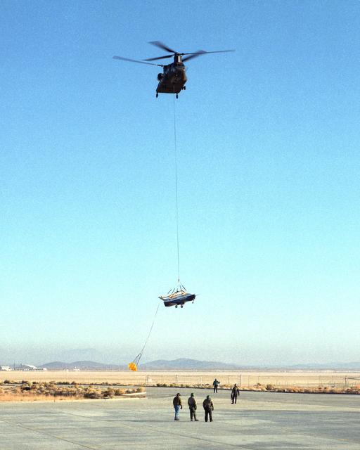 NASA image: A U.S. Army CH-47 Chinook helicopter slowly lowers the X-40 sub-scale technology demonstrator to the ground under the watchful eyes of ground crew at the conclusion of a captive-carry test flight
