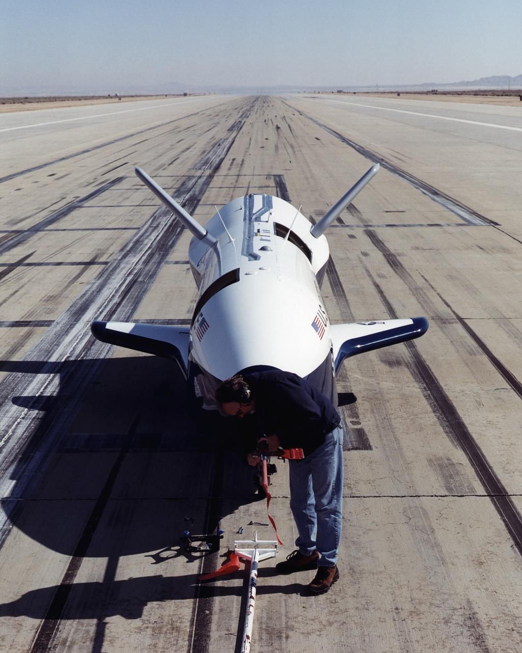 A worker attaches covers for the nose pitot boom before removing the unpiloted X-40 from the runway at Edwards Air Force Base, California, following its successful free-flight on March 14, 2001. The unpiloted X-40 is a risk-reduction vehicle for the X-37, which is intended to be a reusable space vehicle. NASA's Marshall Space Flight Center in Huntsville, Ala, manages the X-37 project. At Dryden, the X-40A will undergo a series of ground and air tests to reduce possible risks to the larger X-37, including drop tests from a helicopter to check guidance and navigation systems planned for use in the X-37. The X-37 is designed to demonstrate technologies in the orbital and reentry environments for next-generation reusable launch vehicles that will increase both safety and reliability, while reducing launch costs from $10,000 per pound to $1,000 per pound.