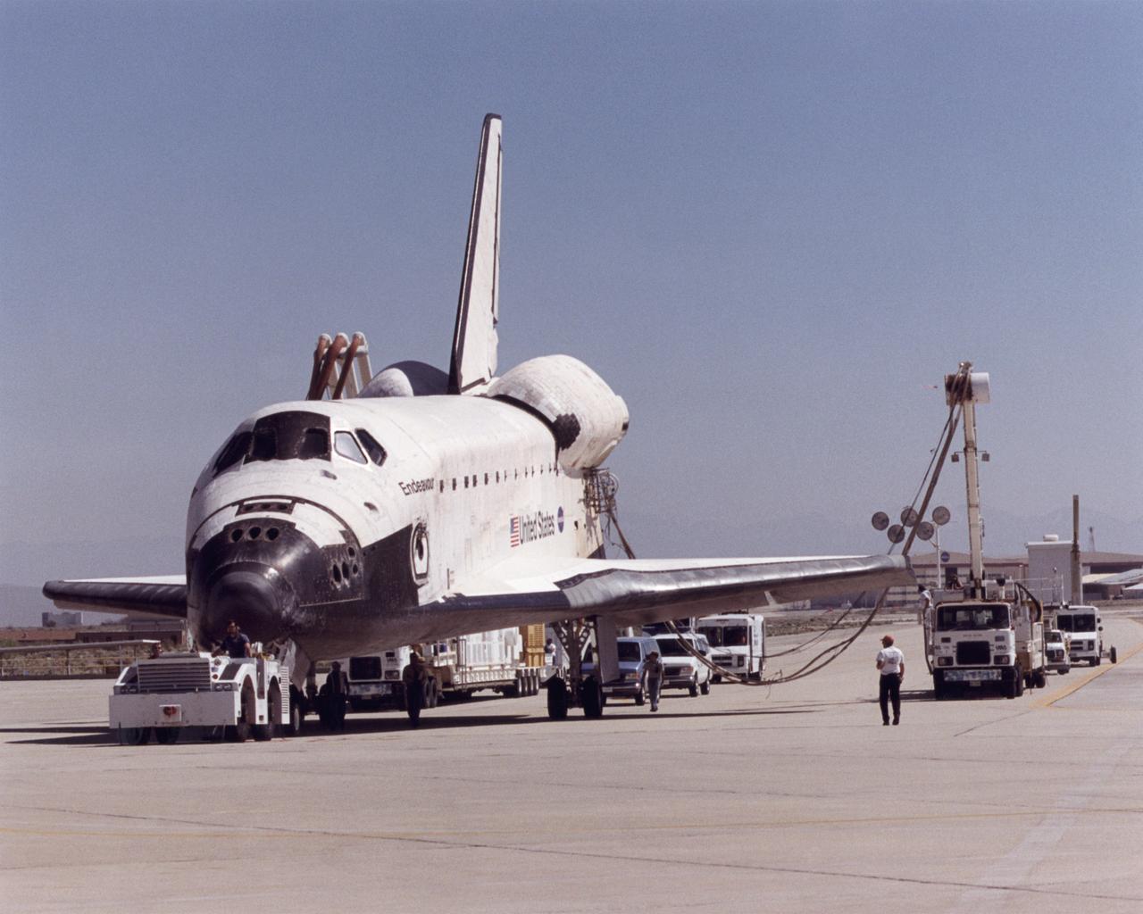 A convoy of specialized support vehicles follow the Space Shuttle Endeavour as it is towed up a taxiway at NASA's Dryden Flight Research Center on Edwards Air Force Base, California, after landing on May 1, 2001. The two largest vehicles trailing the shuttle provide electrical power and air conditioning to the shuttle's systems during post-flight recovery operations. The Endeavour had just completed mission STS-100, an almost 12-day mission to install the Canadarm 2 robotic arm and deliver some three tons of supplies and experiments to the International Space Station. The landing was the 48th shuttle landing at Edwards since shuttle flights began in 1981. After post-flight processing, the Endeavour was mounted atop one of NASA's modified Boeing 747 shuttle carrier aircraft and ferried back to the Kennedy Space Center in Florida on May 8, 2001.