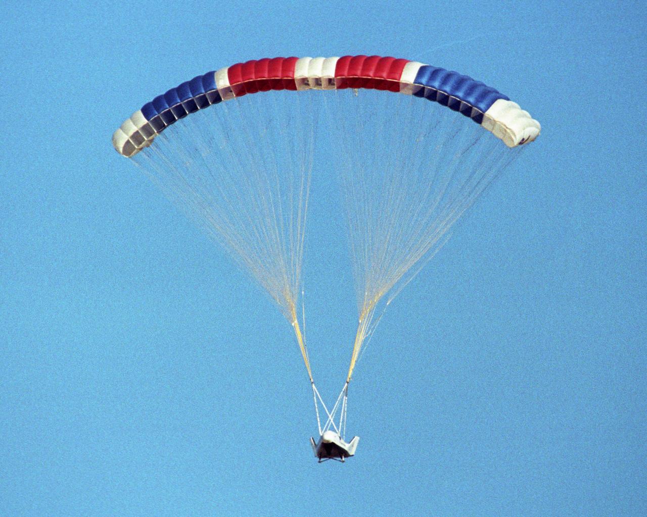 The X-38 prototype of the Crew Return Vehicle for the International Space Station is suspended under its giant 7,500-square-foot parafoil during its eighth free flight on Thursday, Dec. 13, 2001. A portion of the descent was flown by remote control by a NASA astronaut from a ground vehicle configured like the CRV's interior before the X-38 made an autonomous landing on Rogers Dry Lake.
