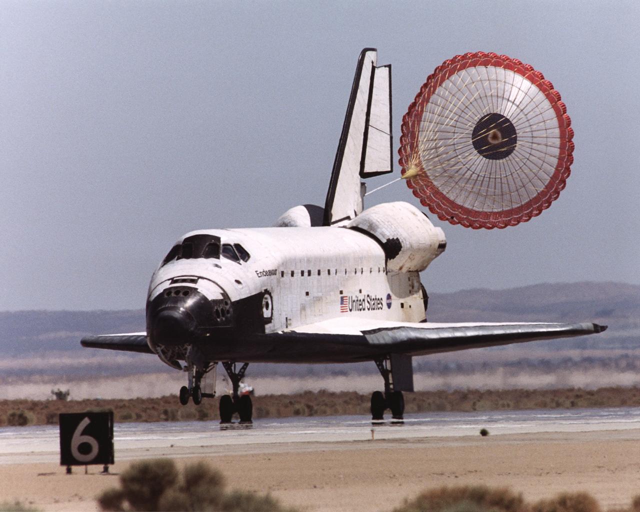 The Space Shuttle Endeavour's drag chute deploys to slow the orbiter as it rolls out on Runway 22 at Edwards Air Force Base at the conclusion of its 14-day STS-111 mission to the International Space Station.