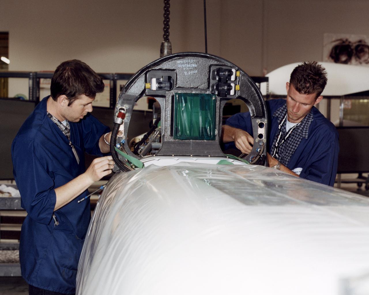 Technicians at General Atomics Aeronautical Systems, Inc., (GA-ASI) facility at Adelanto, Calif., carefully thread control lines through a bulkhead during engine installation on NASA's Altair aircraft.
