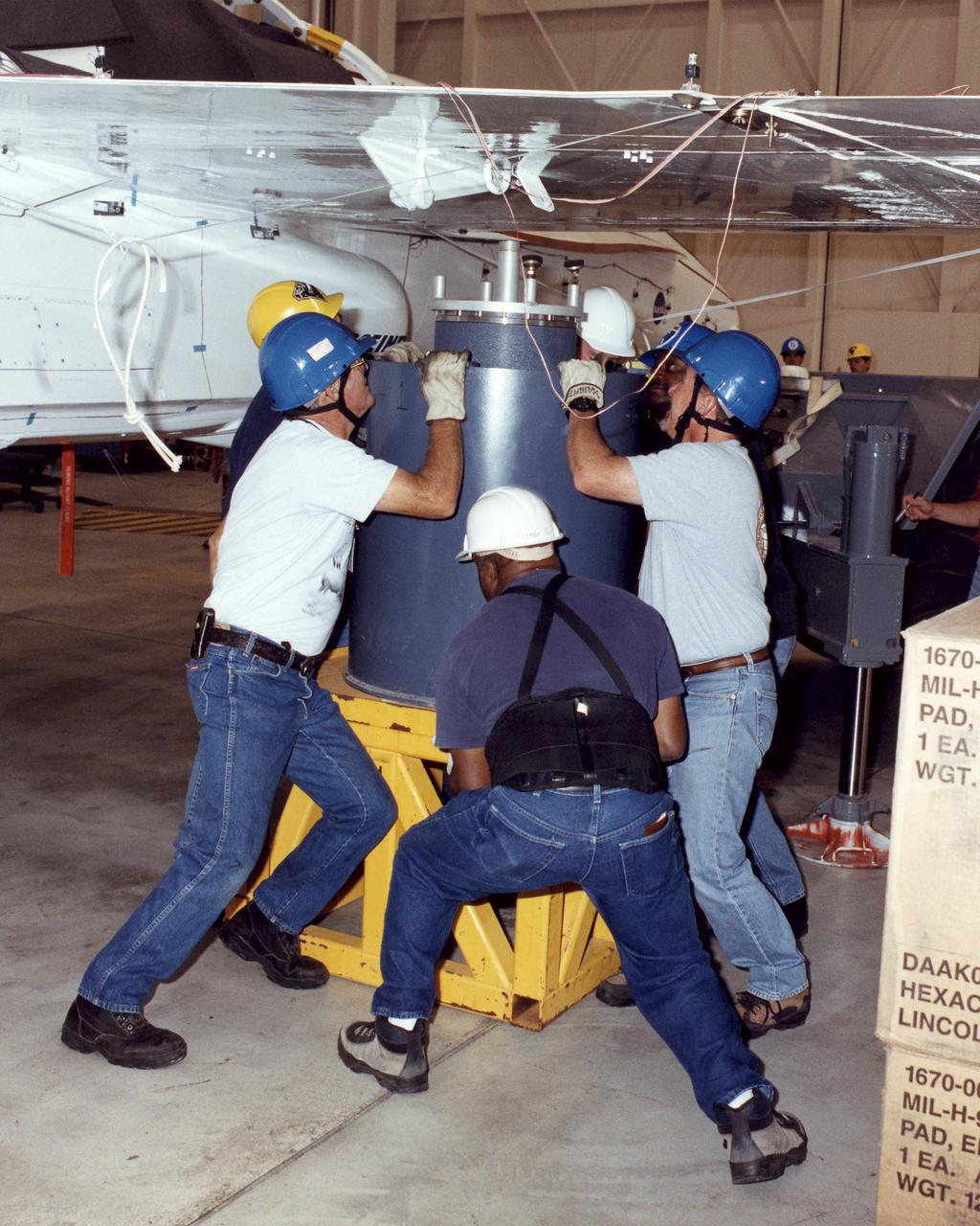 NASA Dryden technicians (Dave Dennis, Freddy Green and Jeff Doughty) position a support cylinder under the right wing of the Active Aeroelastic Wing F/A-18 test aircraft prior to ground vibration tests.