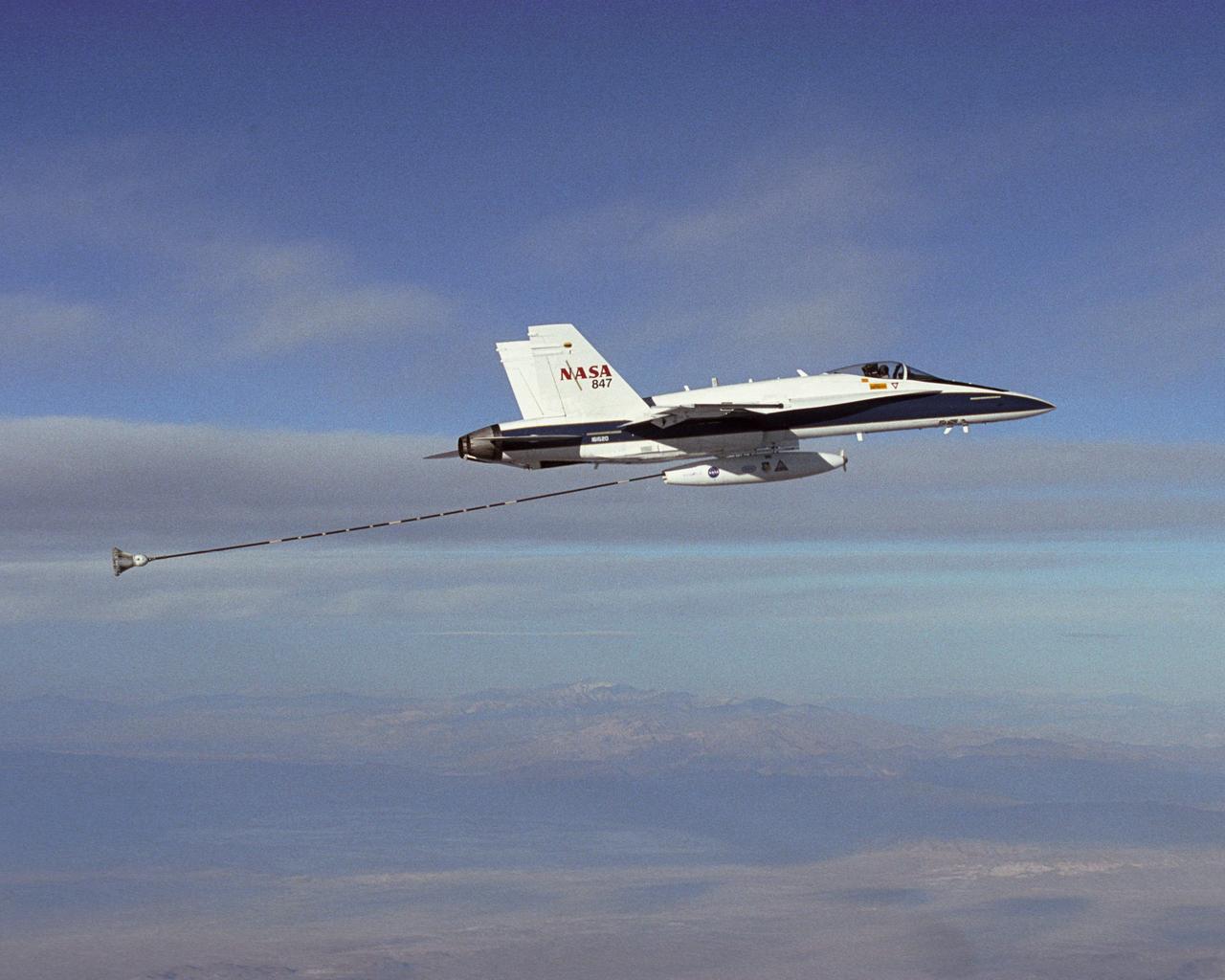 NASA Dryden's Automated Aerial Refueling (AAR) project evaluated the capability of an F/A-18A aircraft as an in-flight refueling tanker with the objective of developing analytical models for an automated aerial refueling system for unmanned air vehicles. The F/A-18 "tanker" aircraft (No. 847) underwent flight test envelope expansion with an aerodynamic pod containing air-refueling equipment carried beneath the fuselage. The second aircraft (No. 843) flew as the receiver aircraft during the study to assess the free-stream hose and drogue dynamics on the F/A-18A.
