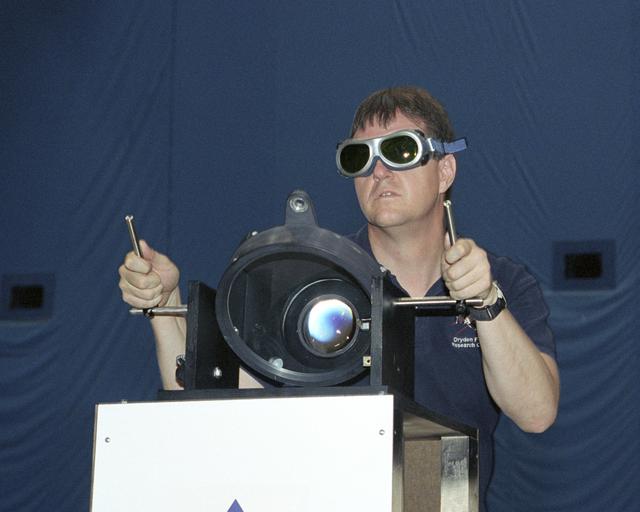 NASA image: NASA Dryden's Dave Bushman aims the optics of a laser device at a panel on a model aircraft during the first flight demonstration of an aircraft powered by laser light.