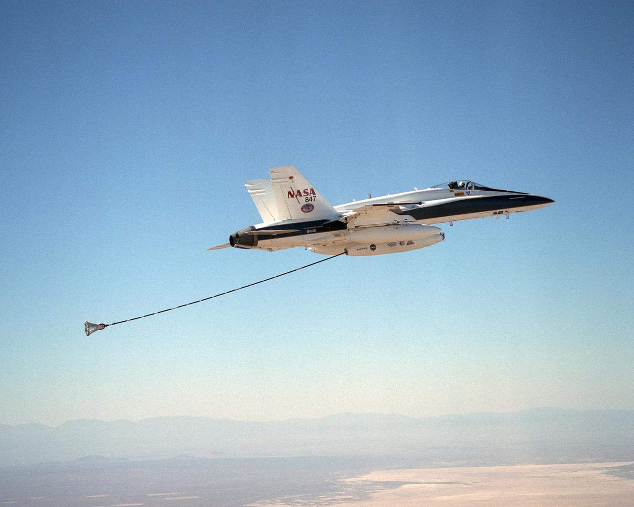 NASA Dryden's Automated Aerial Refueling (AAR) project evaluated the capability of an F/A-18A aircraft as an in-flight refueling tanker with the objective of developing analytical models for an automated aerial refueling system for unmanned air vehicles. The F/A-18 "tanker" aircraft (No. 847) underwent flight test envelope expansion with an aerodynamic pod containing air-refueling equipment carried beneath the fuselage. The second aircraft flew as the receiver aircraft during the study to assess the free-stream hose and drogue dynamics on the F/A-18A.