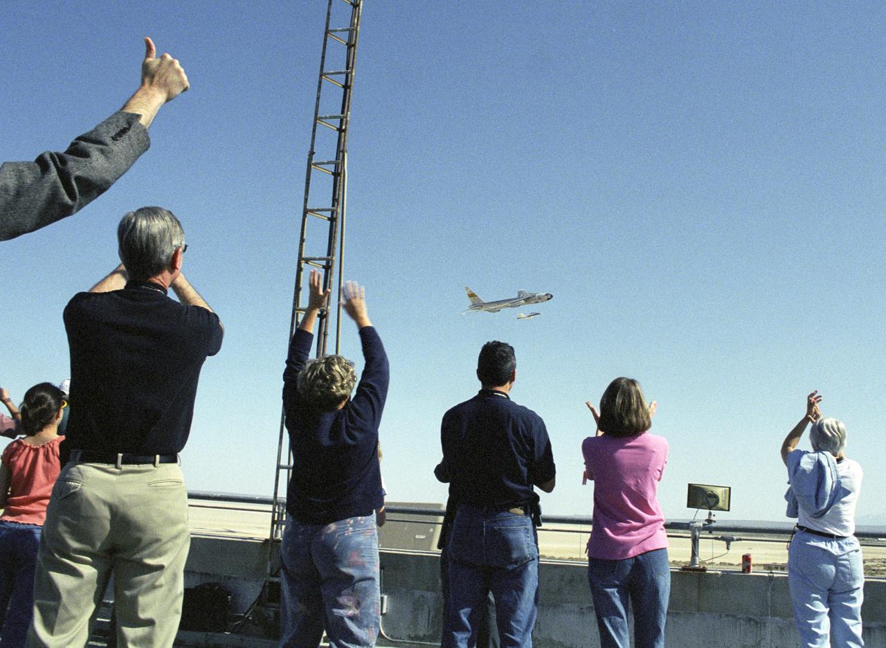 Employees atop NASA Dryden's main building celebrate the return flyby of the B-52B aircraft after it launched the second X-43A aircraft on its successful flight.