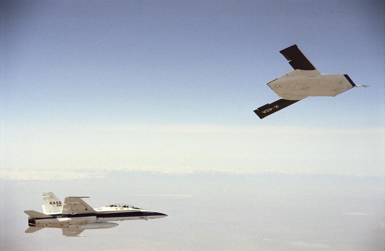 X-45A in flight with F-18 #846 chase aircraft, during first GPS-guided weapon demonstration flight.
