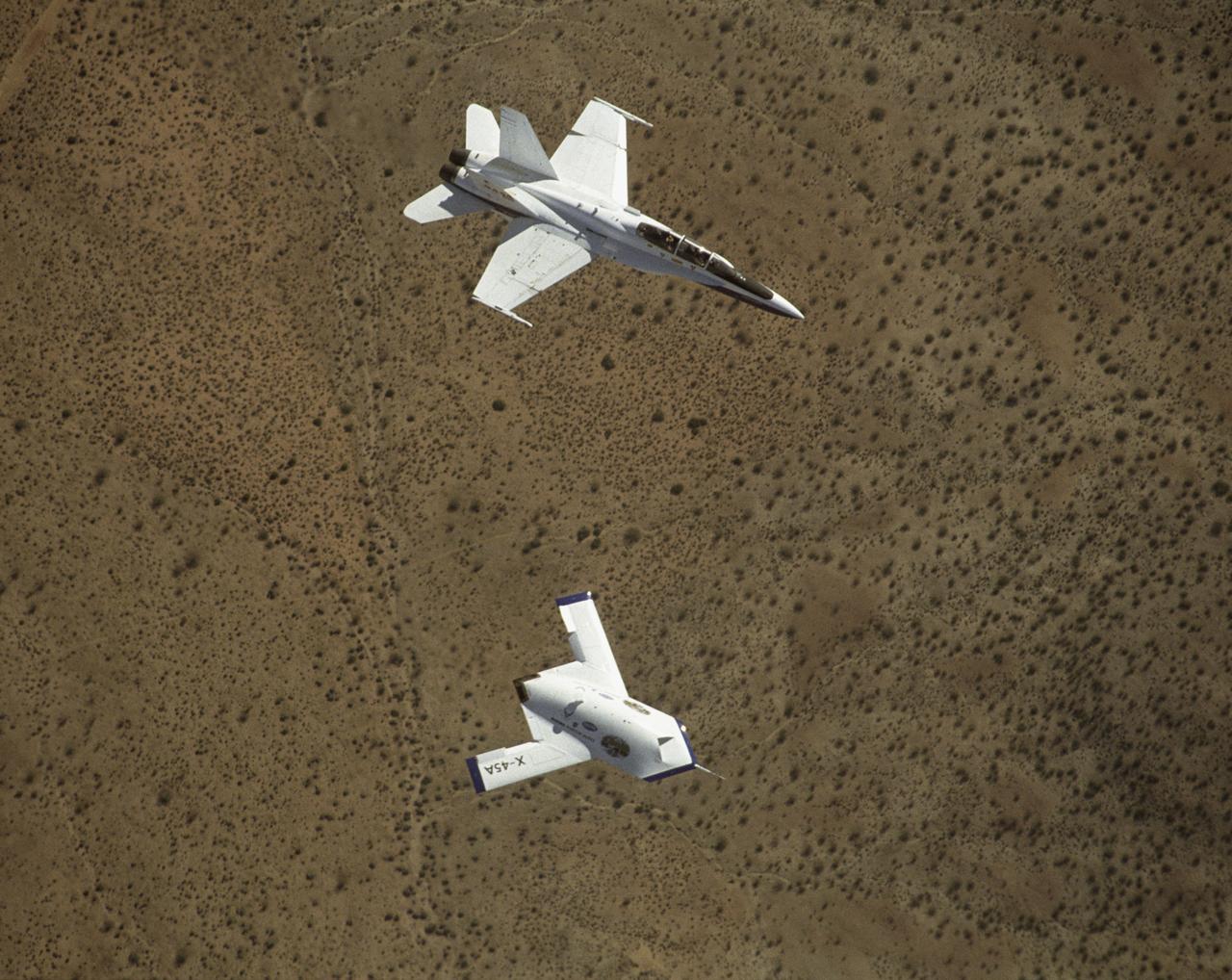 X-45A in flight with F-18 #846 chase aircraft, during first GPS-guided weapon demonstration flight.