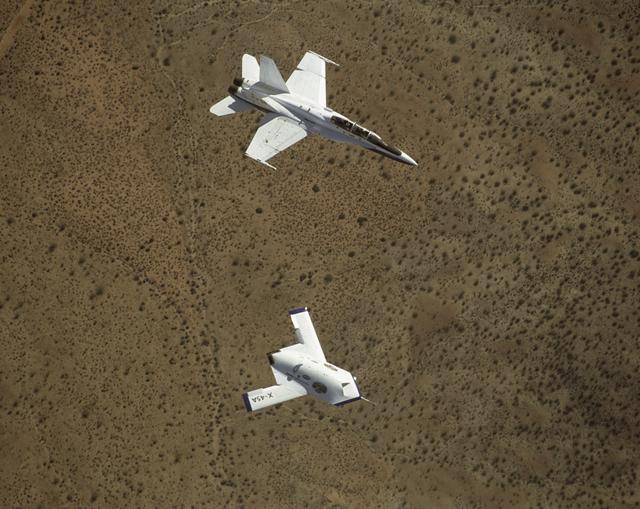 NASA image: X-45A in flight with F-18 #846 chase aircraft, during first GPS-guided weapon demonstration flight