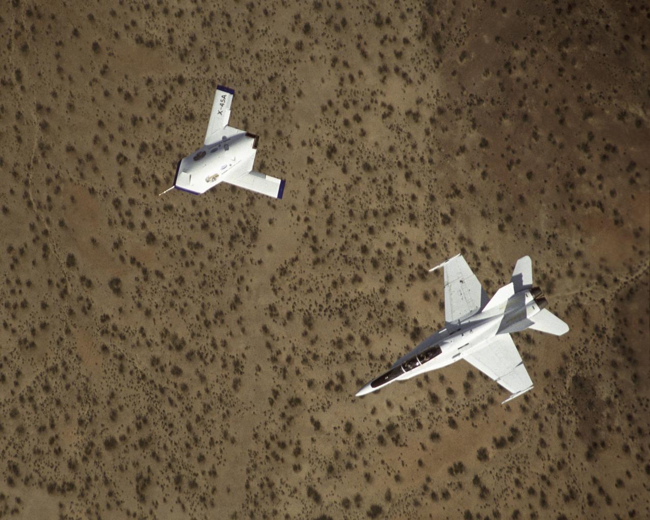 X-45A in flight with F-18 #846 chase aircraft, during first GPS-guided weapon demonstration flight.