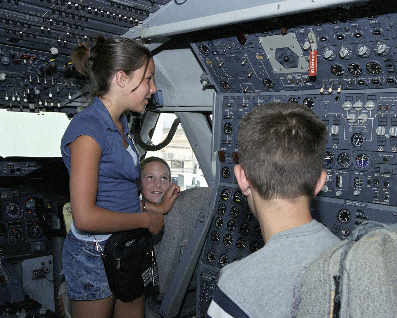 Leah Robson and Bridgette Puljiz of Tehachapi (seated) and Zachary Johnson of Palmdale (back to camera) look over the maze of dials and switches in the flight deck of NASA's modified Boeing 747 space shuttle carrier aircraft during Take Your Children to Work Day June 22 at NASA Dryden Flight Research Center.
