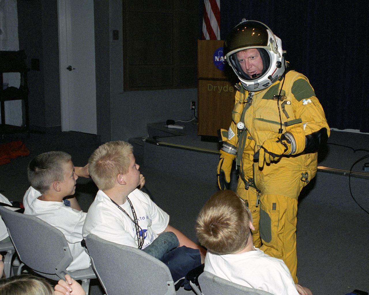 NASA Dryden historian Christian Gelzer explains functions of the high-altitude pressure suit he is wearing to (left to right) Brandon Blankenship and Garrett Clay of Lancaster and Eddie Patterson of Tehachapi during Take Your Children to Work Day activities at NASA Dryden Flight Research Center June 22.