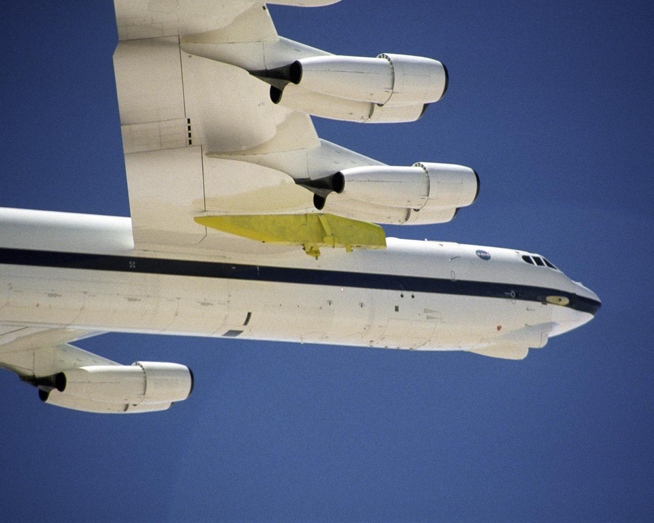 A newly constructed pylon (green) for carrying aerospace vehicles aloft flies attached to the wing of NASA Dryden Flight Research Center's B-52H aircraft.