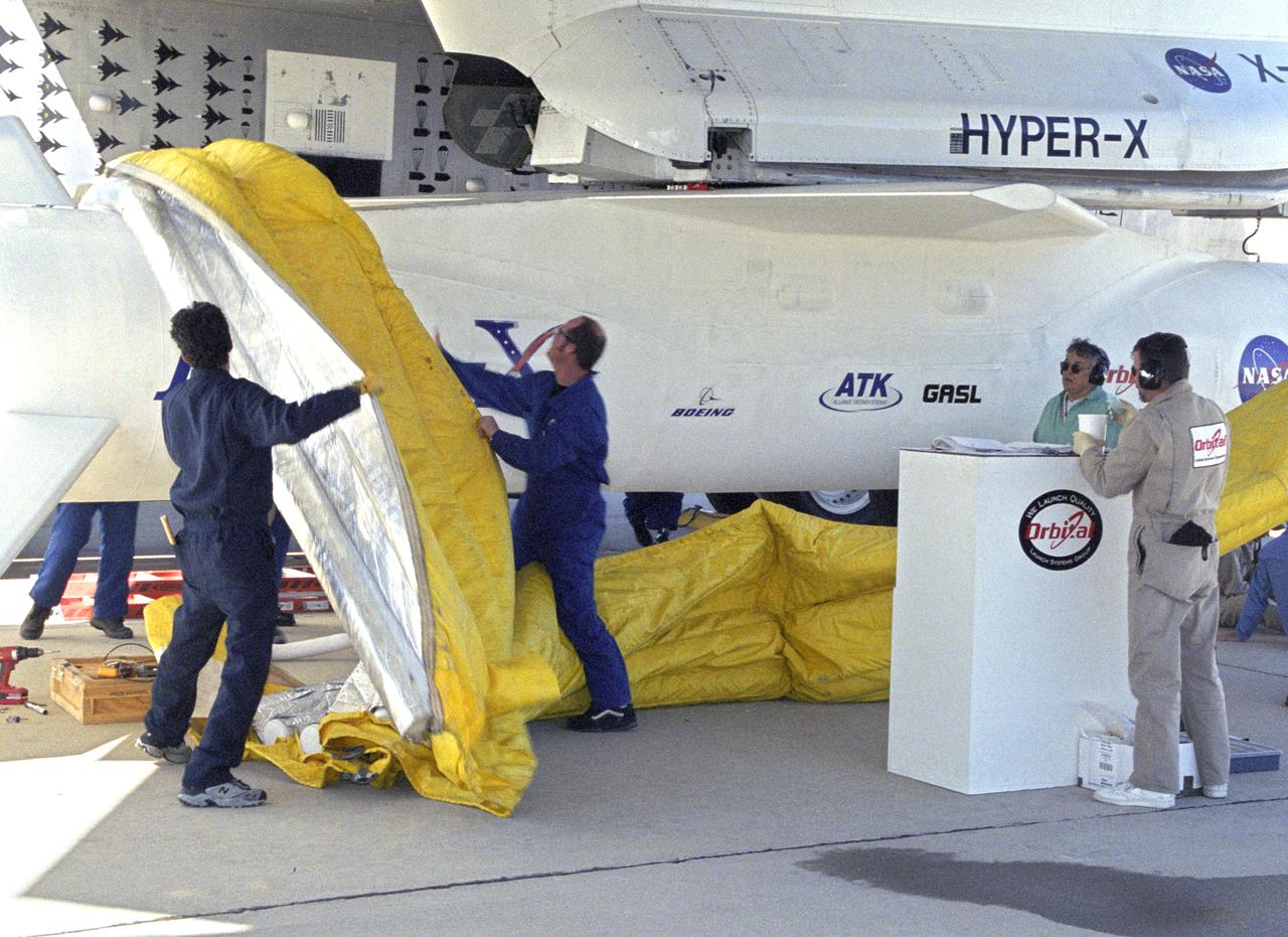 Orbital Sciences Corp. technicians remove protective shrouds from the modified Pegasus booster before takeoff on the X-43A's Mach 9.6 record scramjet flight.