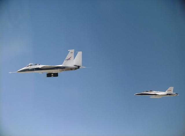 NASA image: NASA's F-15B carrying thermal insulation foam on its flight test fixture is shadowed by a NASA F-18B chase aircraft during a LIFT experiment research flight.