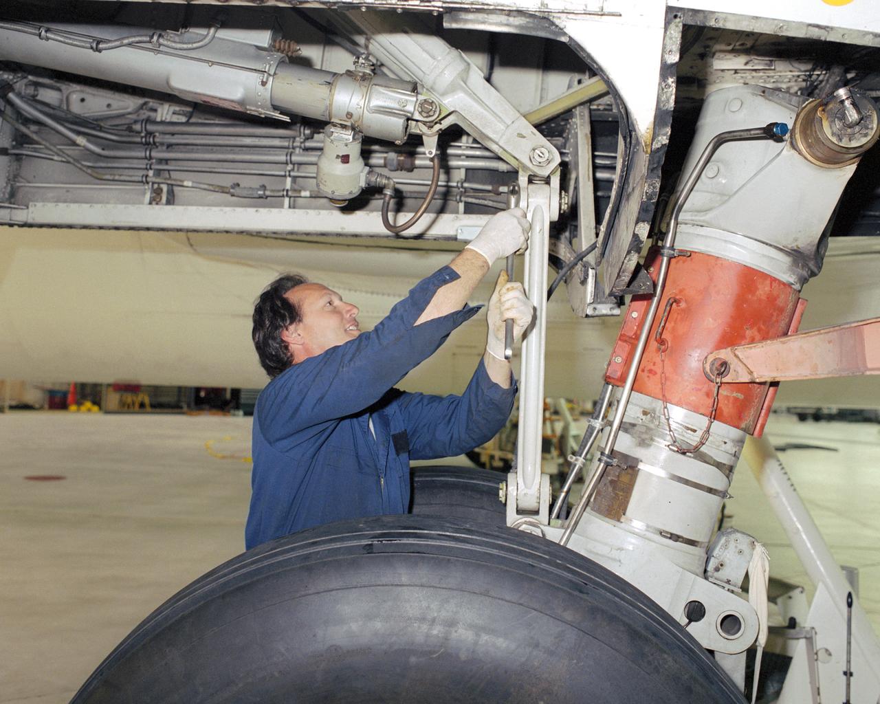 Assistant crew chief David Wyckoff applies some elbow grease to loosen a link pin during a landing gear changeout on NASA Johnson Space Center's Super Guppy.