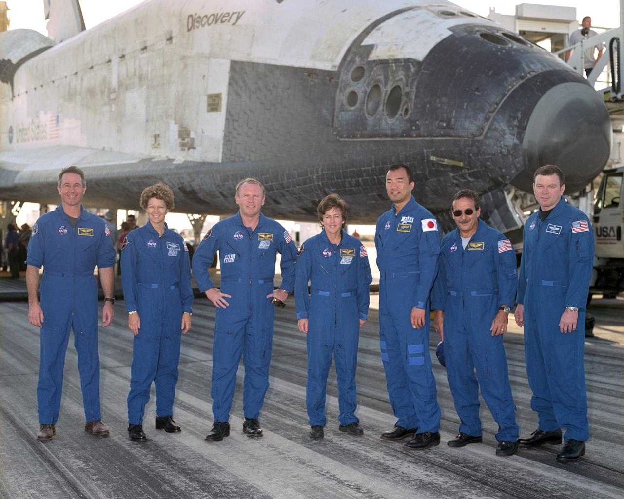 The crew of Space Shuttle mission STS-114 gathered in front of the shuttle Discovery following landing at Edwards Air Force Base, California, August 9, 2005. From left to right: Mission Specialist Stephen Robinson, Commander Eileen Collins, Mission Specialists Andrew Thomas, Wendy Lawrence, Soichi Noguchi and Charles Camarda, and Pilot James Kelly.  Space Shuttle Discovery landed safely at NASA's Dryden Flight Research Center at Edwards Air Force Base in California at 5:11:22 a.m. PDT this morning, following the very successful 14-day STS-114 return to flight mission.  During their two weeks in space, Commander Eileen Collins and her six crewmates tested out new safety procedures and delivered supplies and equipment the International Space Station.  Discovery spent two weeks in space, where the crew demonstrated new methods to inspect and repair the Shuttle in orbit. The crew also delivered supplies, outfitted and performed maintenance on the International Space Station. A number of these tasks were conducted during three spacewalks.  In an unprecedented event, spacewalkers were called upon to remove protruding gap fillers from the heat shield on Discovery's underbelly. In other spacewalk activities, astronauts installed an external platform onto the Station's Quest Airlock and replaced one of the orbital outpost's Control Moment Gyroscopes.  Inside the Station, the STS-114 crew conducted joint operations with the Expedition 11 crew. They unloaded fresh supplies from the Shuttle and the Raffaello Multi-Purpose Logistics Module. Before Discovery undocked, the crews filled Raffeallo with unneeded items and returned to Shuttle payload bay.  Discovery launched on July 26 and spent almost 14 days on orbit.