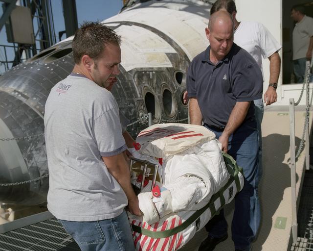 NASA image: Technicians Ray Smith and Raphael Rodriguez remove one of the Extravehicular Mobility Units from the Space Shuttle Discovery after its landing at NASA Dryden