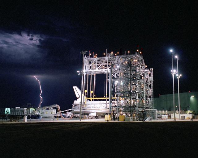 NASA image: Lightning strikes in the distance as the Space Shuttle Discovery receives post-flight processing in the Mate-Demate Device, following its landing at NASA DFRC
