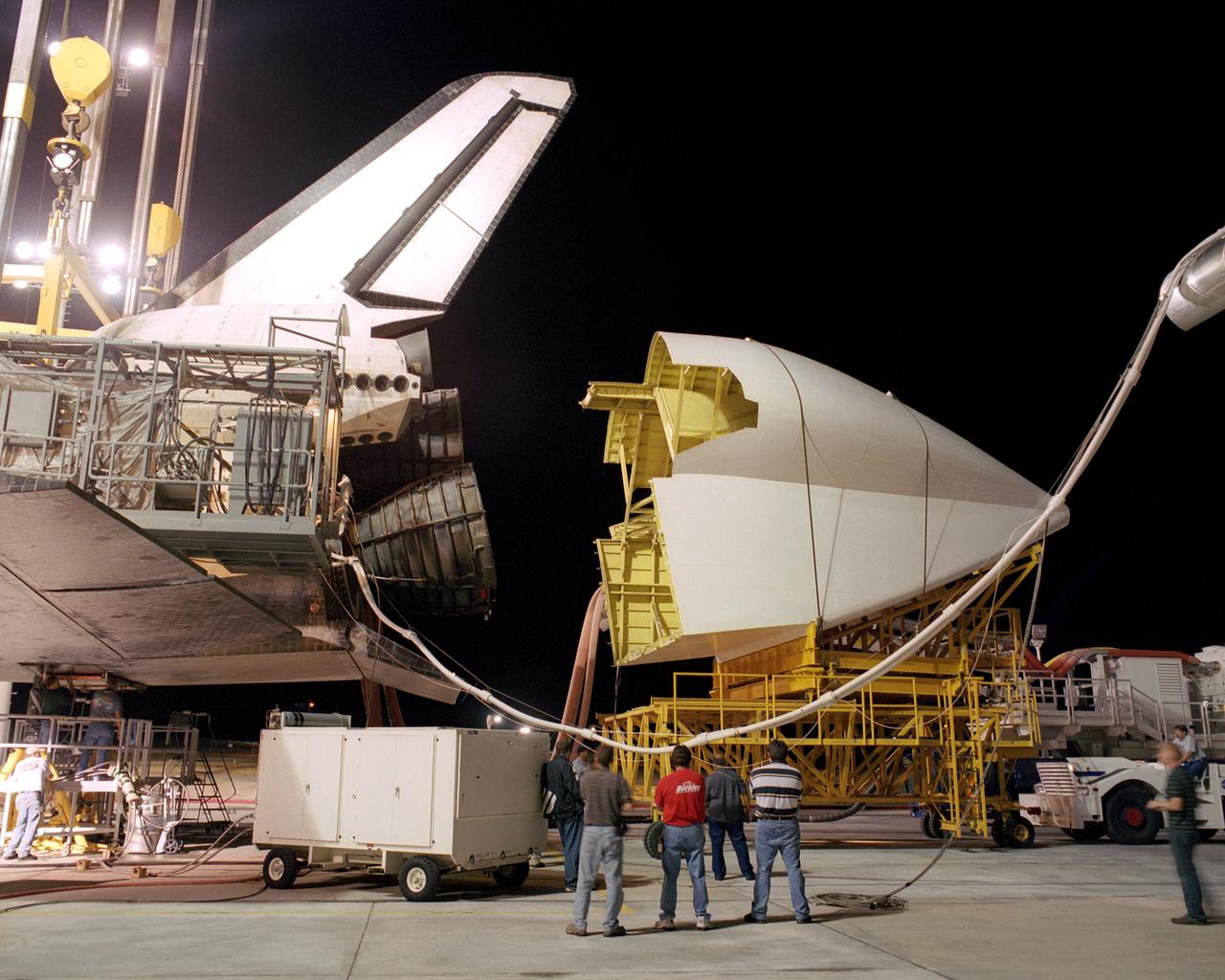 Workers position the tail cone on the Space Shuttle Discovery in preparation for its return to NASA's Kennedy Space Center in Florida. After the tail-cone is installed, Discovery will be mounted on NASA's modified Boeing 747 Shuttle Carrier Aircraft, or SCA, for the return flight. The tail cone is a fitting that helps reduce aerodynamic drag and turbulence during its ferry flight. Space Shuttle Discovery landed safely at NASA's Dryden Flight Research Center at Edwards Air Force Base in California at 5:11:22 a.m. PDT, August 9, 2005, following the very successful 14-day STS-114 return to flight mission.  During their two weeks in space, Commander Eileen Collins and her six crewmates tested out new safety procedures and delivered supplies and equipment the International Space Station.  Discovery spent two weeks in space, where the crew demonstrated new methods to inspect and repair the Shuttle in orbit. The crew also delivered supplies, outfitted and performed maintenance on the International Space Station. A number of these tasks were conducted during three spacewalks.  In an unprecedented event, spacewalkers were called upon to remove protruding gap fillers from the heat shield on Discovery's underbelly. In other spacewalk activities, astronauts installed an external platform onto the Station's Quest Airlock and replaced one of the orbital outpost's Control Moment Gyroscopes.  Inside the Station, the STS-114 crew conducted joint operations with the Expedition 11 crew. They unloaded fresh supplies from the Shuttle and the Raffaello Multi-Purpose Logistics Module. Before Discovery undocked, the crews filled Raffeallo with unneeded items and returned to Shuttle payload bay.  Discovery launched on July 26 and spent almost 14 days on orbit.