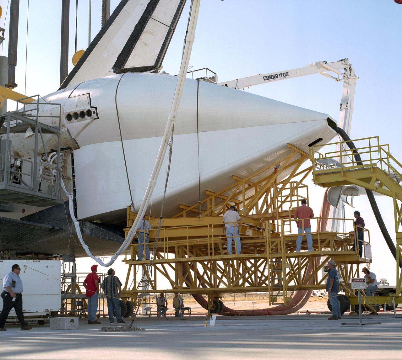 Technicians attach the tail cone, which helps reduce aerodynamic drag and turbulence during its ferry flight, to the Space Shuttle Discovery in preparation for its return to NASA's Kennedy Space Center in Florida. After the tail-cone is installed, Discovery will be mounted on NASA's modified Boeing 747 Shuttle Carrier Aircraft, or SCA, for the return flight. Space Shuttle Discovery landed safely at NASA's Dryden Flight Research Center at Edwards Air Force Base in California at 5:11:22 a.m. PDT, August 9, 2005, following the very successful 14-day STS-114 return to flight mission.  During their two weeks in space, Commander Eileen Collins and her six crewmates tested out new safety procedures and delivered supplies and equipment the International Space Station.  Discovery spent two weeks in space, where the crew demonstrated new methods to inspect and repair the Shuttle in orbit. The crew also delivered supplies, outfitted and performed maintenance on the International Space Station. A number of these tasks were conducted during three spacewalks.  In an unprecedented event, spacewalkers were called upon to remove protruding gap fillers from the heat shield on Discovery's underbelly. In other spacewalk activities, astronauts installed an external platform onto the Station's Quest Airlock and replaced one of the orbital outpost's Control Moment Gyroscopes.  Inside the Station, the STS-114 crew conducted joint operations with the Expedition 11 crew. They unloaded fresh supplies from the Shuttle and the Raffaello Multi-Purpose Logistics Module. Before Discovery undocked, the crews filled Raffeallo with unneeded items and returned to Shuttle payload bay.  Discovery launched on July 26 and spent almost 14 days on orbit.