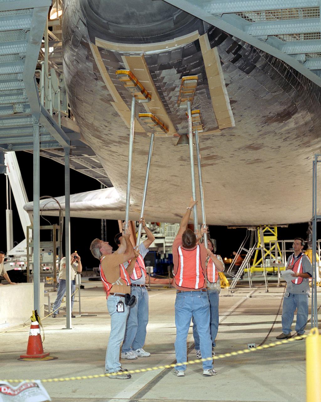 Closing the landing gear doors is one of the final servicing steps before lifting of the Space Shuttle Discovery and mating it to NASA's 747 can begin. After being raised in the gantry-like Mate-Demate Device (MDD), Discovery will be mounted on NASA's modified Boeing 747 Shuttle Carrier Aircraft, or SCA, for the return flight to the Kennedy Space Center in Florida.  Space Shuttle Discovery landed safely at NASA's Dryden Flight Research Center at Edwards Air Force Base in California at 5:11:22 a.m. PDT, August 9, 2005, following the very successful 14-day STS-114 return to flight mission.  During their two weeks in space, Commander Eileen Collins and her six crewmates tested out new safety procedures and delivered supplies and equipment the International Space Station.  Discovery spent two weeks in space, where the crew demonstrated new methods to inspect and repair the Shuttle in orbit. The crew also delivered supplies, outfitted and performed maintenance on the International Space Station. A number of these tasks were conducted during three spacewalks.  In an unprecedented event, spacewalkers were called upon to remove protruding gap fillers from the heat shield on Discovery's underbelly. In other spacewalk activities, astronauts installed an external platform onto the Station's Quest Airlock and replaced one of the orbital outpost's Control Moment Gyroscopes.  Inside the Station, the STS-114 crew conducted joint operations with the Expedition 11 crew. They unloaded fresh supplies from the Shuttle and the Raffaello Multi-Purpose Logistics Module. Before Discovery undocked, the crews filled Raffeallo with unneeded items and returned to Shuttle payload bay.  Discovery launched on July 26 and spent almost 14 days on orbit.