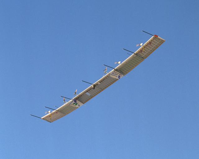 With sensor booms projecting ahead of the wing, the Pathfinder-Plus soars under a blue sky on a turbulence measurement research flight.