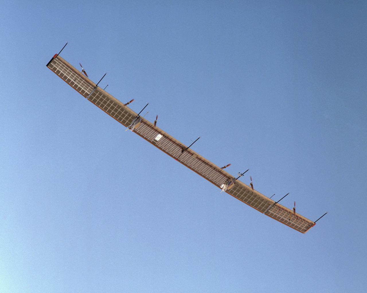With its sensor booms projecting ahead of the wing, the Pathfinder-Plus solar wing soars under a blue sky on its final turbulence measurement research flight.